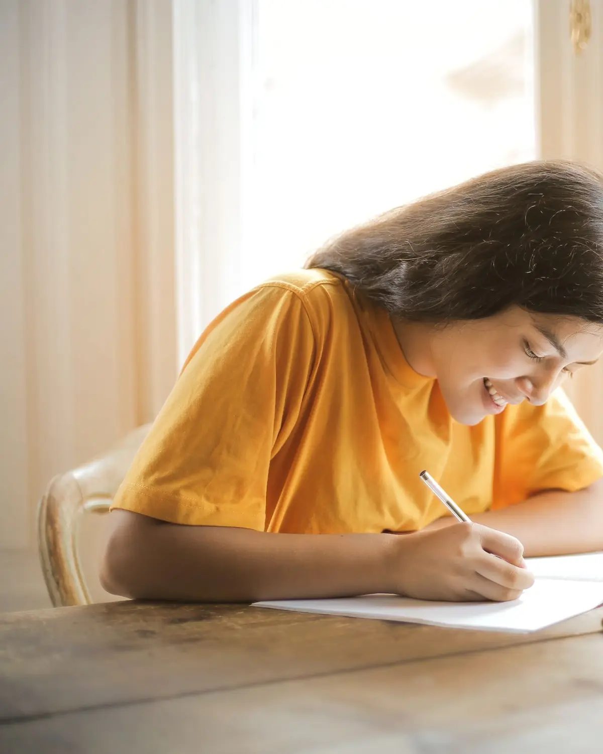 A learner studying at a desk in warm window light, laptop open